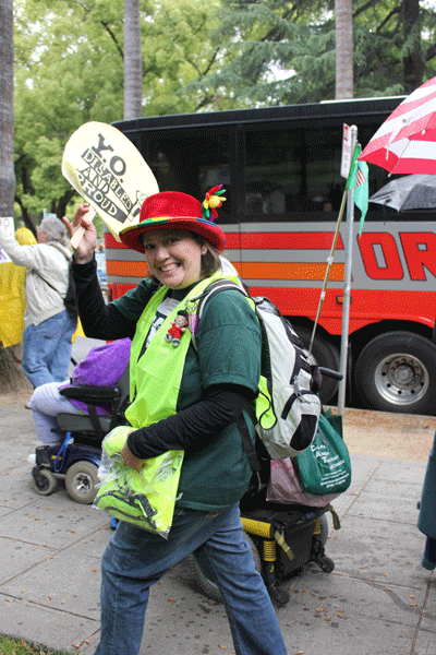 Photo of a smiling woman holding up a YO! Disabled & Proud sign.